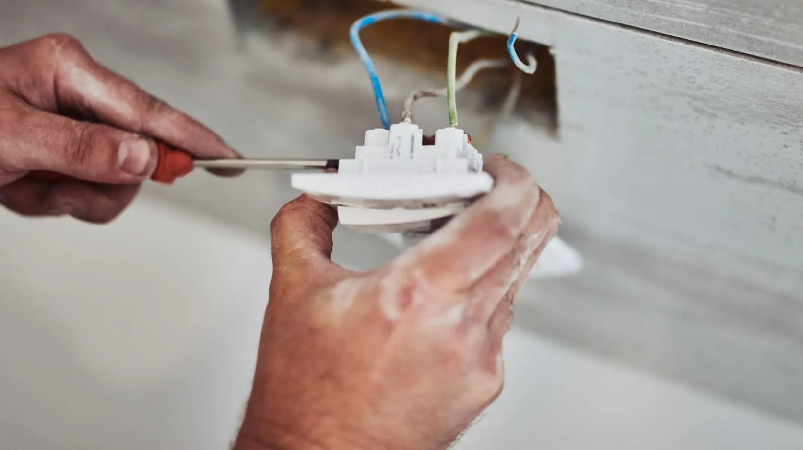 Hands working on wiring during an electrical repair